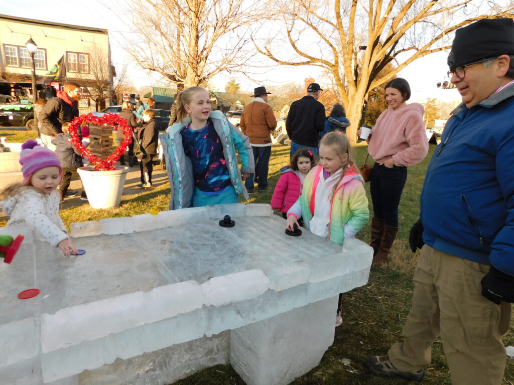 Children playing air hockey on table made of ice